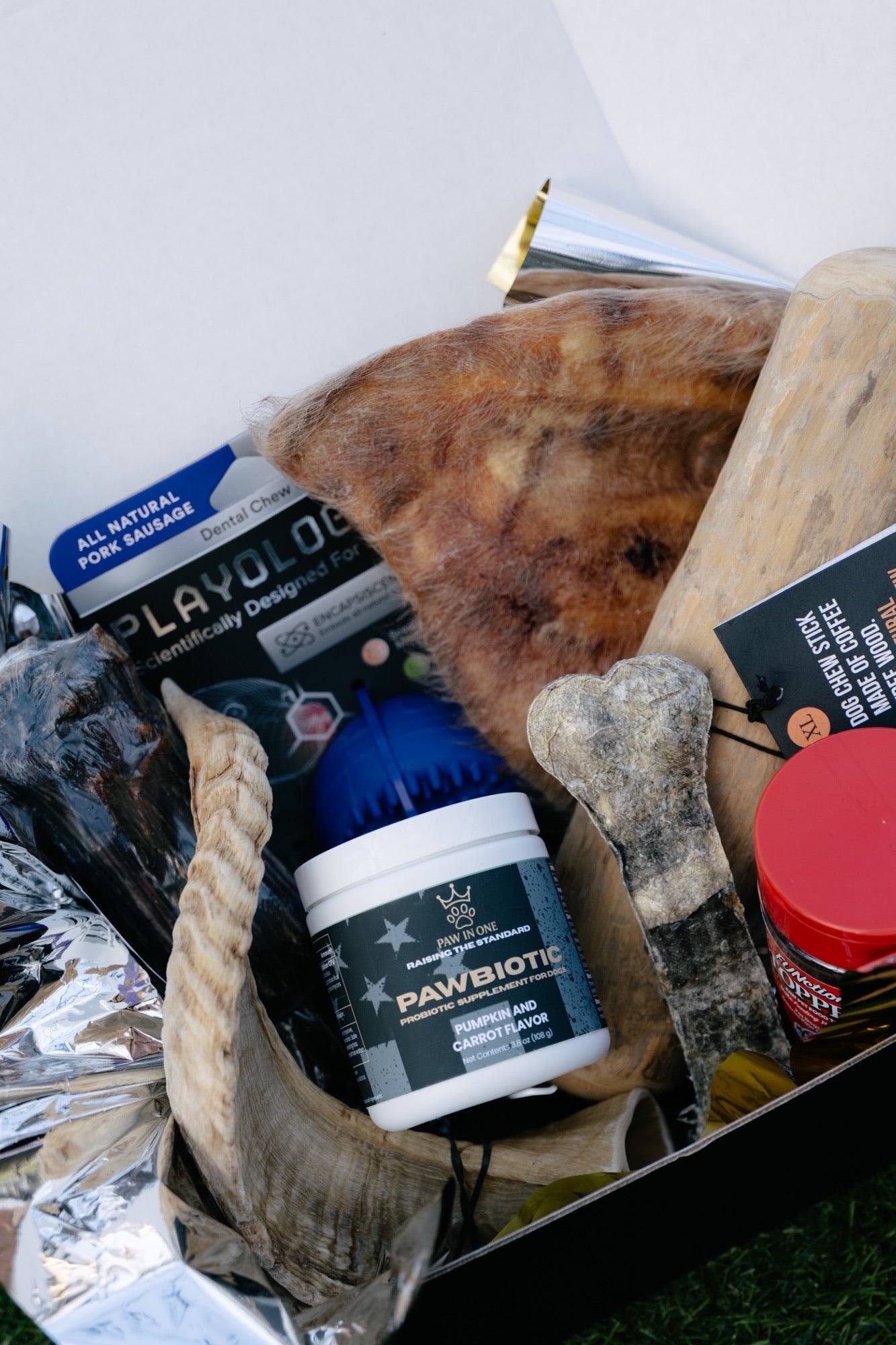 Assorted pet care products including a container labeled 'PAWBIOTIC' on a white surface.